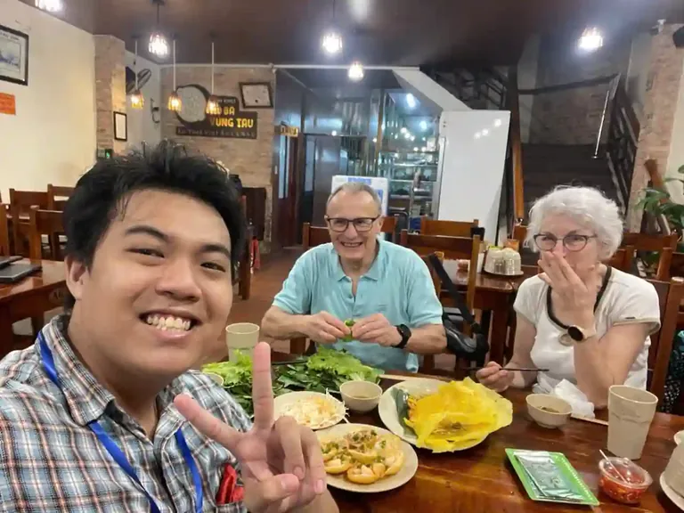 Travelers sharing banh xeo and Vietnamese dishes during a local food experience