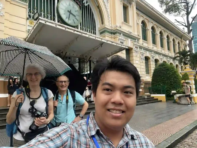 Tony guiding international visitors outside the Central Post Office in Ho Chi Minh City